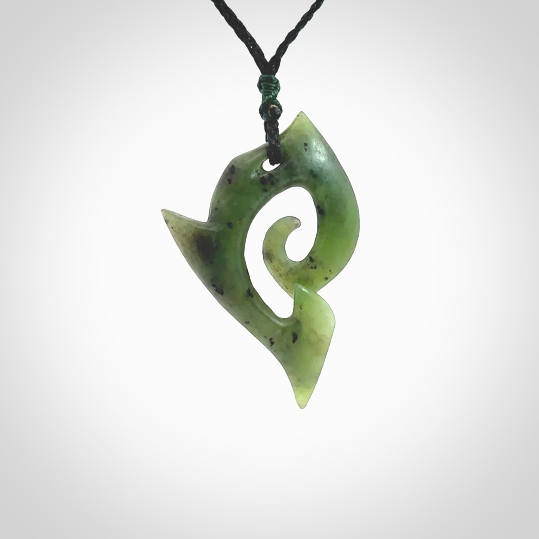 This photo shows a koru pendant carved from New Zealand Jade. The artist, Shaun Gardiner, has carved this beautifully. We provide this piece with an adjustable olive black cord. This is a fantastic work of art, we have one only.