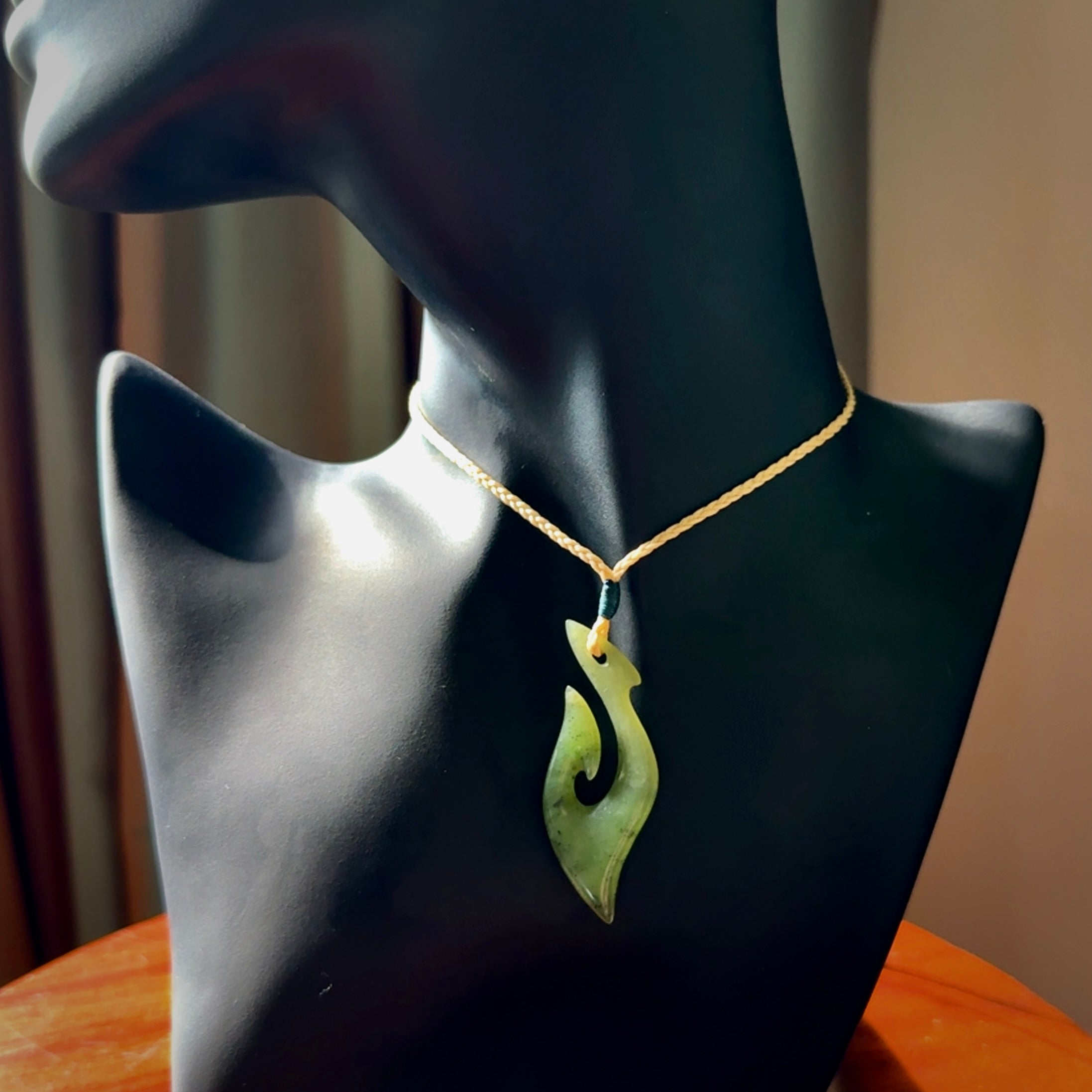 This photo shows a matau pendant carved from New Zealand Kawakawa Jade. The artist, Shaun Gardiner, has carved this beautifully. We provide this piece with an adjustable oat coloured cord. This is a fantastic work of art, we have one only.