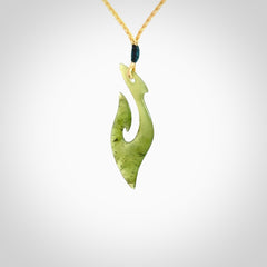 This photo shows a matau pendant carved from New Zealand Kawakawa Jade. The artist, Shaun Gardiner, has carved this beautifully. We provide this piece with an adjustable oat coloured cord. This is a fantastic work of art, we have one only.