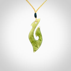 This photo shows a matau pendant carved from New Zealand Kawakawa Jade. The artist, Shaun Gardiner, has carved this beautifully. We provide this piece with an adjustable oat coloured cord. This is a fantastic work of art, we have one only.