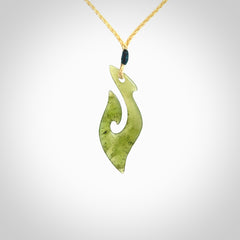 This photo shows a matau pendant carved from New Zealand Kawakawa Jade. The artist, Shaun Gardiner, has carved this beautifully. We provide this piece with an adjustable oat coloured cord. This is a fantastic work of art, we have one only.