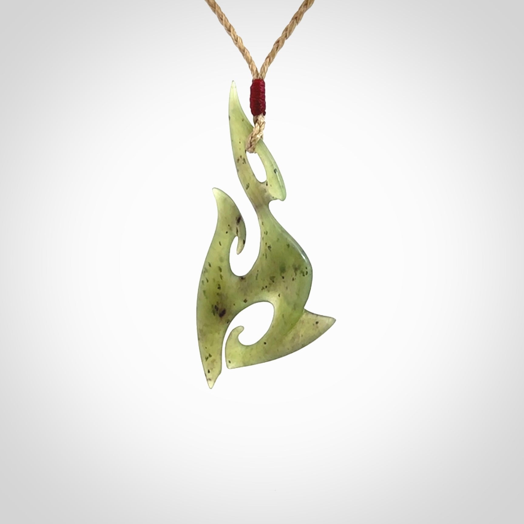 This photo shows a contemporary matau pendant carved from New Zealand Jade. The artist, Shaun Gardiner, has carved this beautifully. We provide this piece with an adjustable tan cord. This is a fantastic work of art, we have one only.