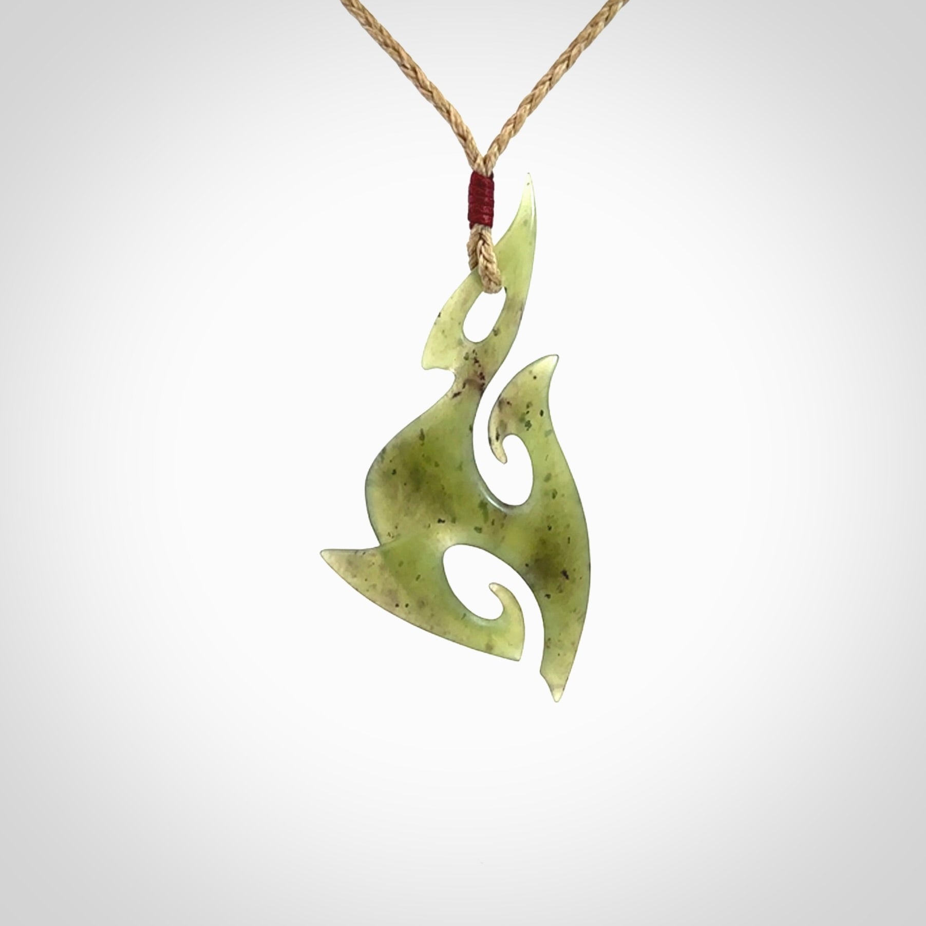 This photo shows a contemporary matau pendant carved from New Zealand Jade. The artist, Shaun Gardiner, has carved this beautifully. We provide this piece with an adjustable tan cord. This is a fantastic work of art, we have one only.