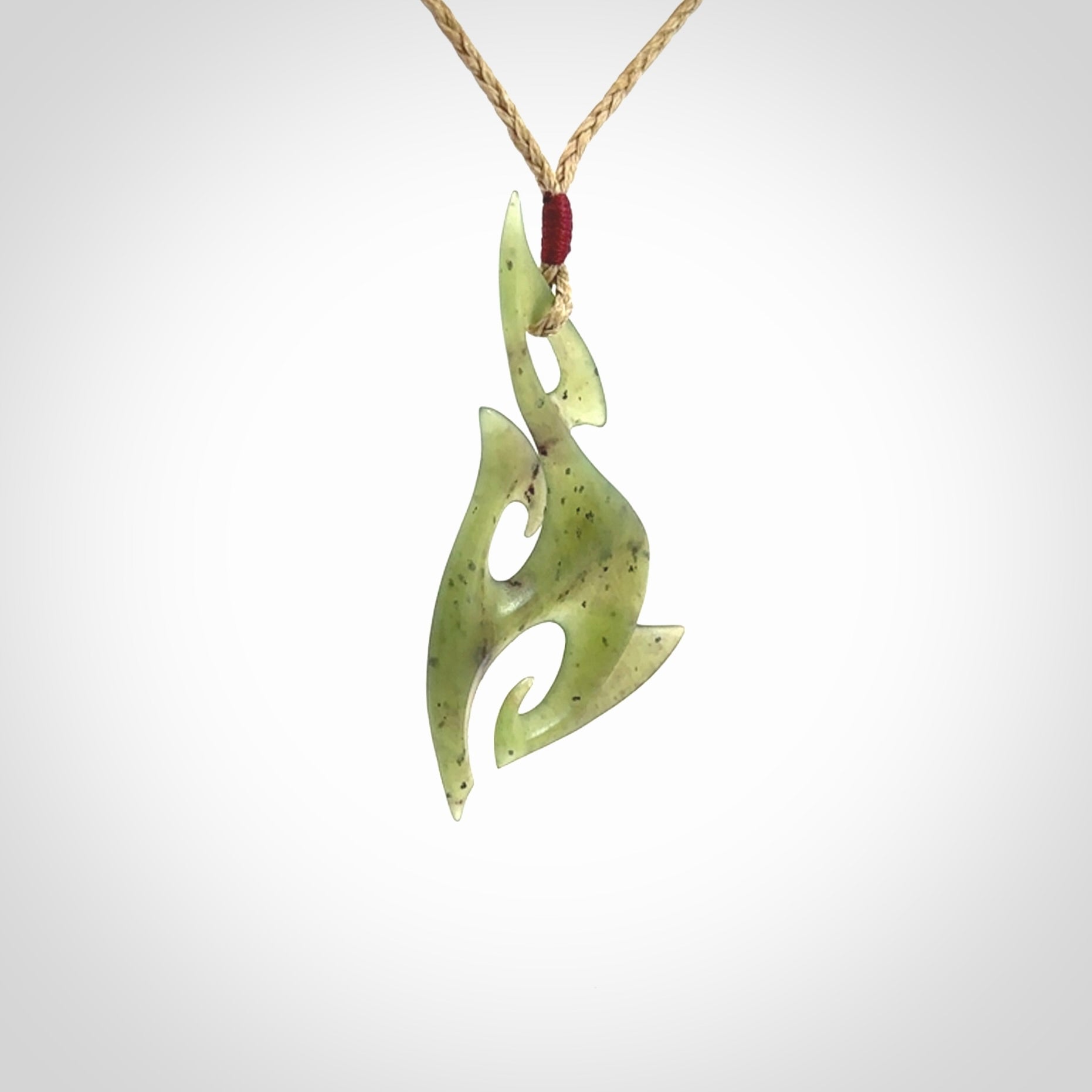 This photo shows a contemporary matau pendant carved from New Zealand Jade. The artist, Shaun Gardiner, has carved this beautifully. We provide this piece with an adjustable tan cord. This is a fantastic work of art, we have one only.