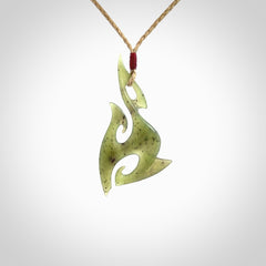 This photo shows a contemporary matau pendant carved from New Zealand Jade. The artist, Shaun Gardiner, has carved this beautifully. We provide this piece with an adjustable tan cord. This is a fantastic work of art, we have one only.