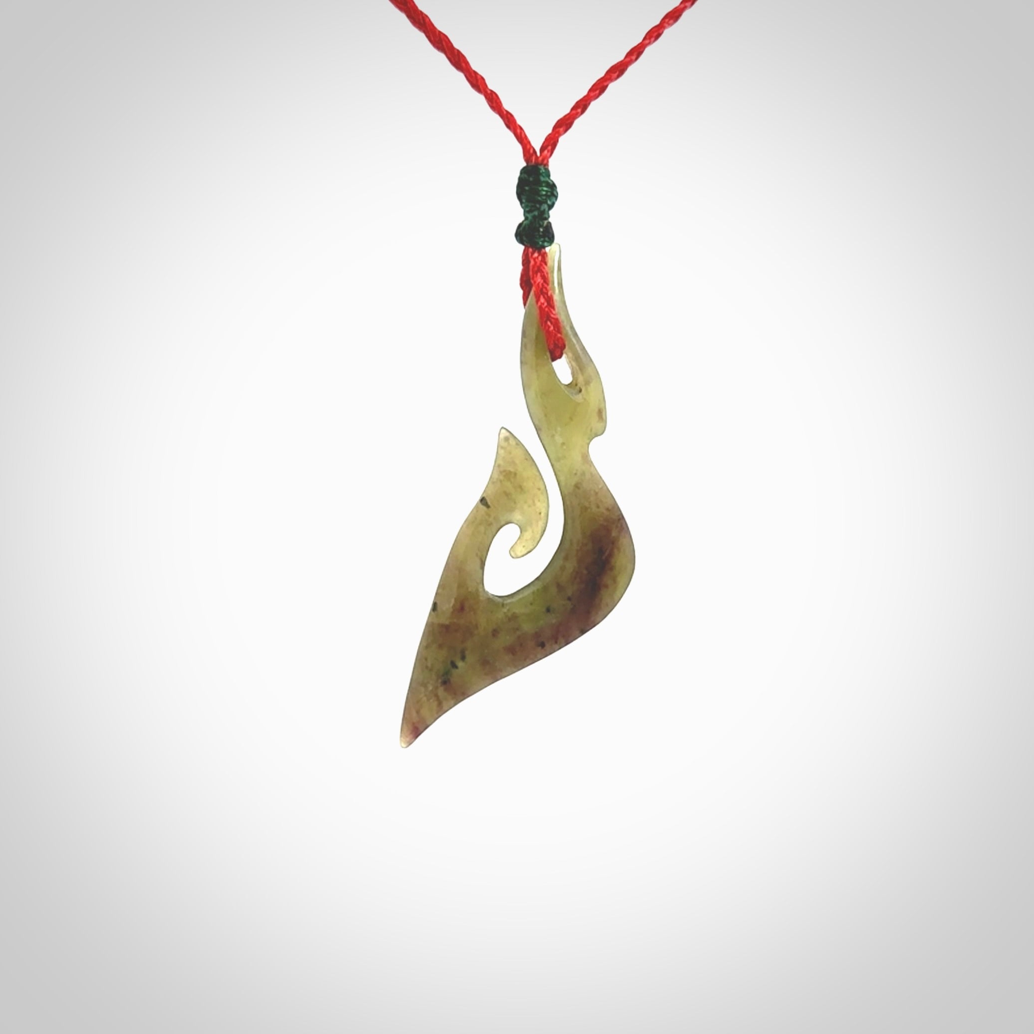 This photo shows a matau pendant carved from New Zealand Totoweka Pounamu, Jade. The artist, Shaun Gardiner, has carved this beautifully. We provide this piece with an adjustable red coloured cord. This is a fantastic work of art, we have one only.