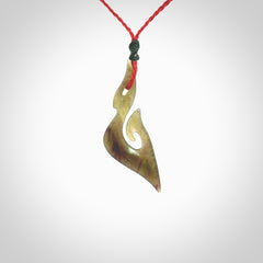 This photo shows a matau pendant carved from New Zealand Totoweka Pounamu, Jade. The artist, Shaun Gardiner, has carved this beautifully. We provide this piece with an adjustable red coloured cord. This is a fantastic work of art, we have one only.