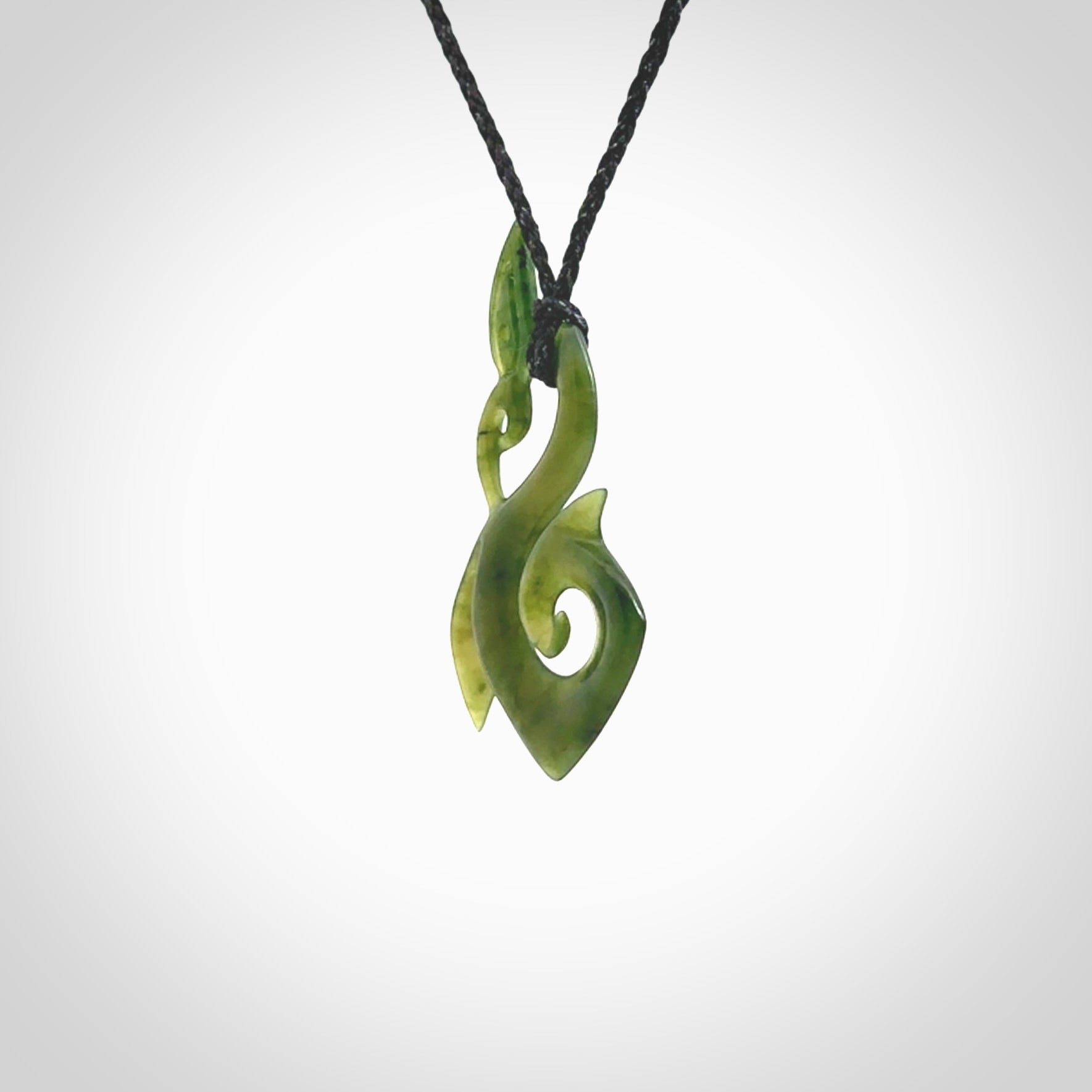 A beautiful jade manaia with koru pendant carved in New Zealand Jade. The pendant is suspended from a plaited black coloured cord. The cord is length adjustable so you can position the pendant where it suits you best. One only.