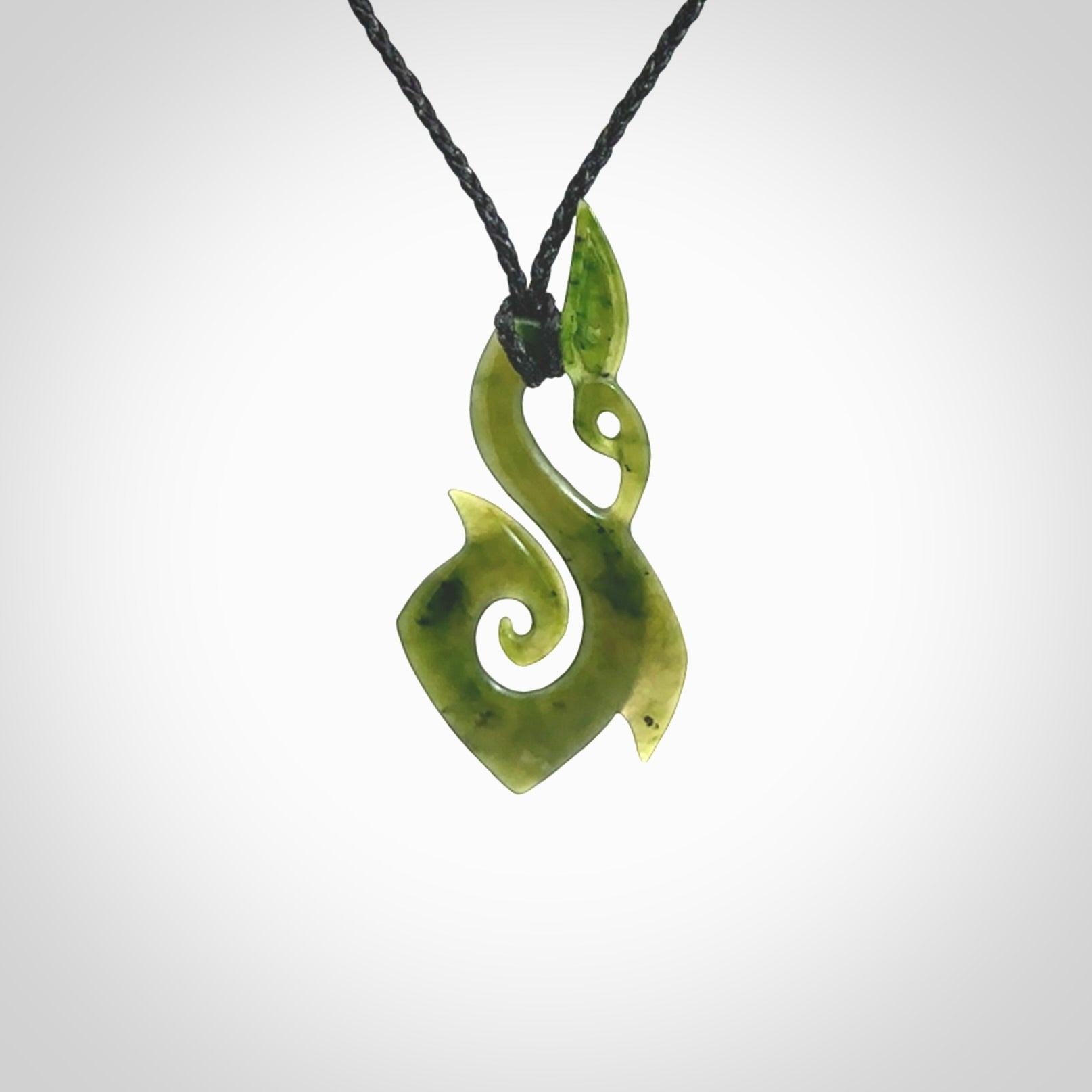 A beautiful jade manaia with koru pendant carved in New Zealand Jade. The pendant is suspended from a plaited black coloured cord. The cord is length adjustable so you can position the pendant where it suits you best. One only.