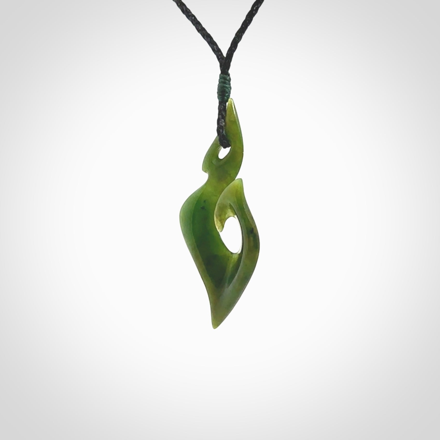 This photo shows a matau pendant carved from New Zealand Pounamu, Jade. The artist, Shaun Gardiner, has carved this beautifully. We provide this piece with an adjustable black coloured cord. This is a fantastic work of art, we have one only.