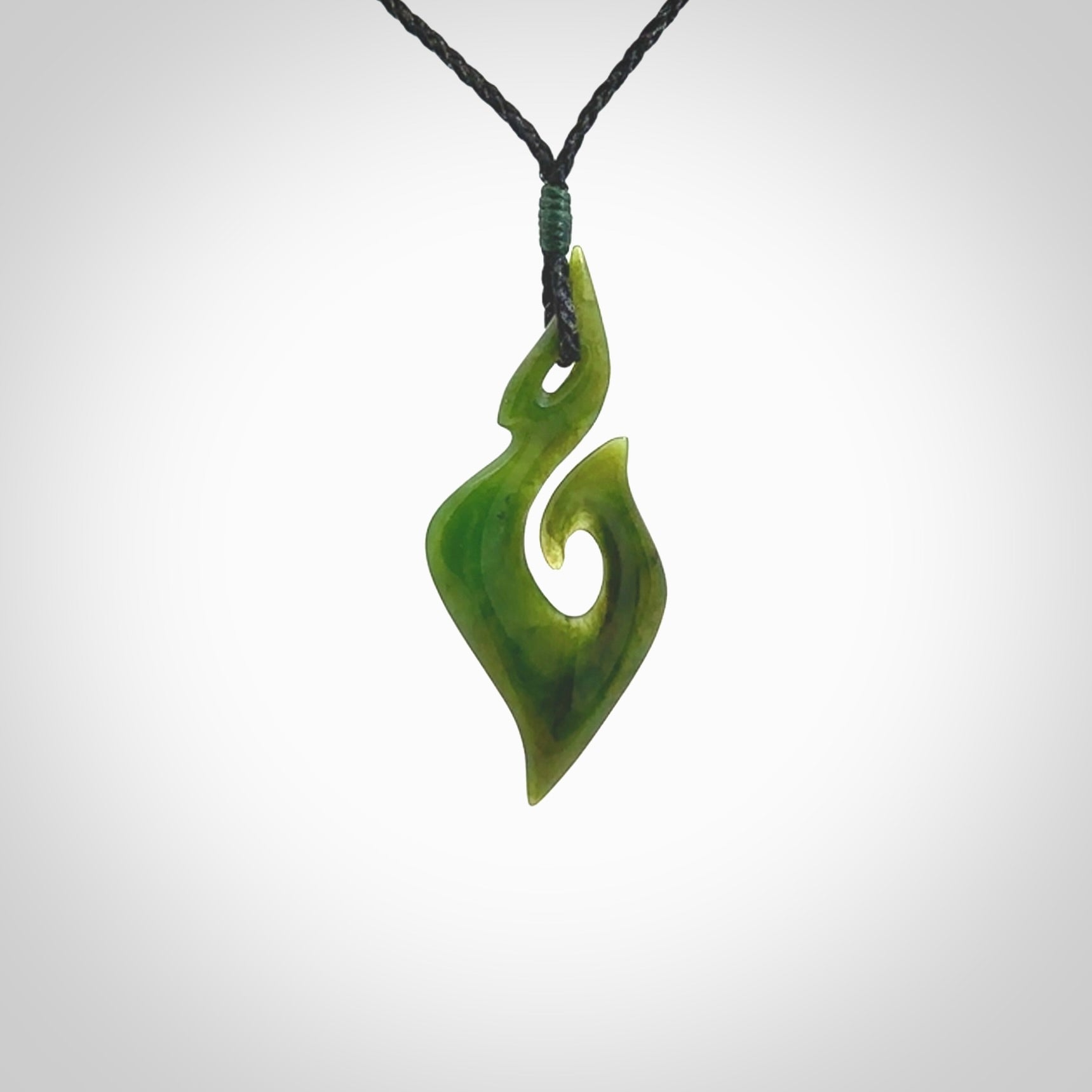 This photo shows a matau pendant carved from New Zealand Pounamu, Jade. The artist, Shaun Gardiner, has carved this beautifully. We provide this piece with an adjustable black coloured cord. This is a fantastic work of art, we have one only.