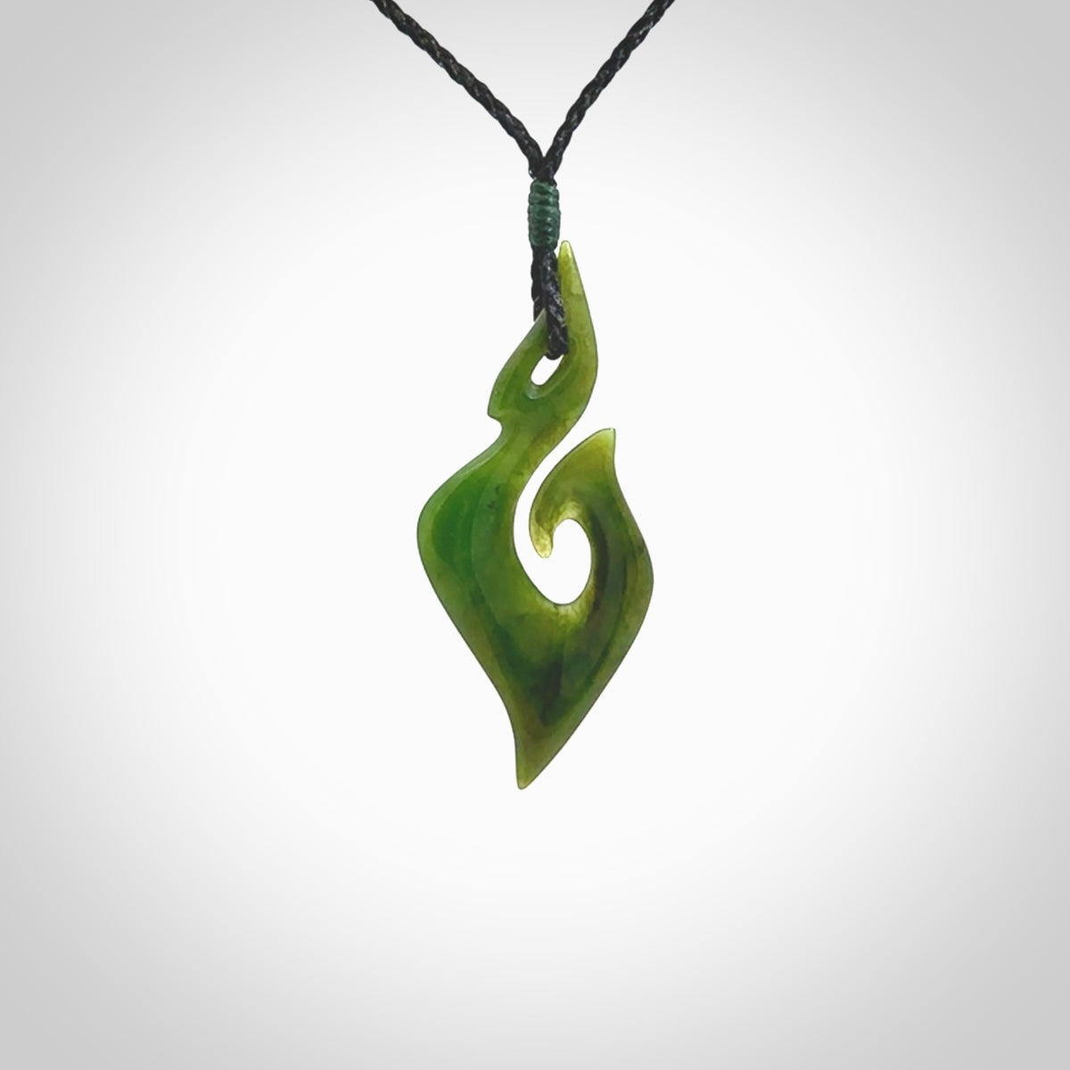 This photo shows a matau pendant carved from New Zealand Pounamu, Jade. The artist, Shaun Gardiner, has carved this beautifully. We provide this piece with an adjustable black coloured cord. This is a fantastic work of art, we have one only.