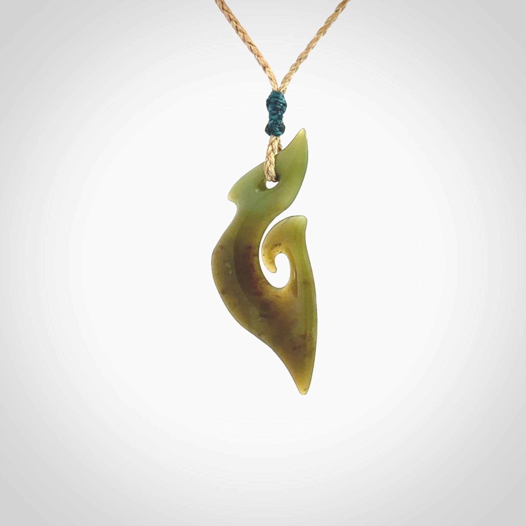 This photo shows a matau pendant carved from New Zealand Totoweka Pounamu, Jade. The artist, Shaun Gardiner, has carved this beautifully. We provide this piece with an adjustable tan coloured cord. This is a fantastic work of art, we have one only.