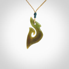 This photo shows a matau pendant carved from New Zealand Totoweka Pounamu, Jade. The artist, Shaun Gardiner, has carved this beautifully. We provide this piece with an adjustable tan coloured cord. This is a fantastic work of art, we have one only.