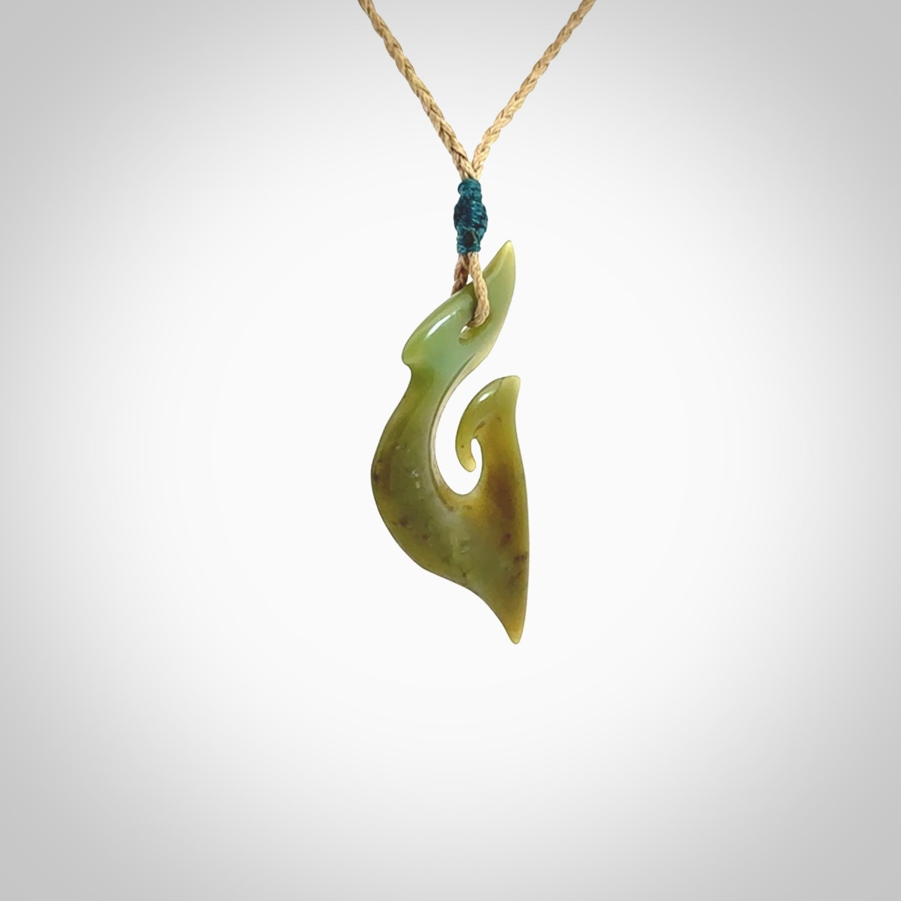 This photo shows a matau pendant carved from New Zealand Totoweka Pounamu, Jade. The artist, Shaun Gardiner, has carved this beautifully. We provide this piece with an adjustable tan coloured cord. This is a fantastic work of art, we have one only.