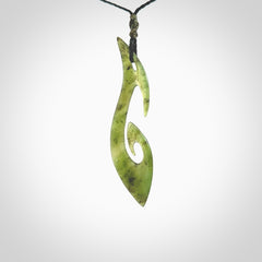 This photo shows a large contemporary matau pendant carved from New Zealand Jade. The artist, Shaun Gardiner, has carved this beautifully. We provide this piece with an adjustable black coloured cord. This is a fantastic work of art, we have one only.