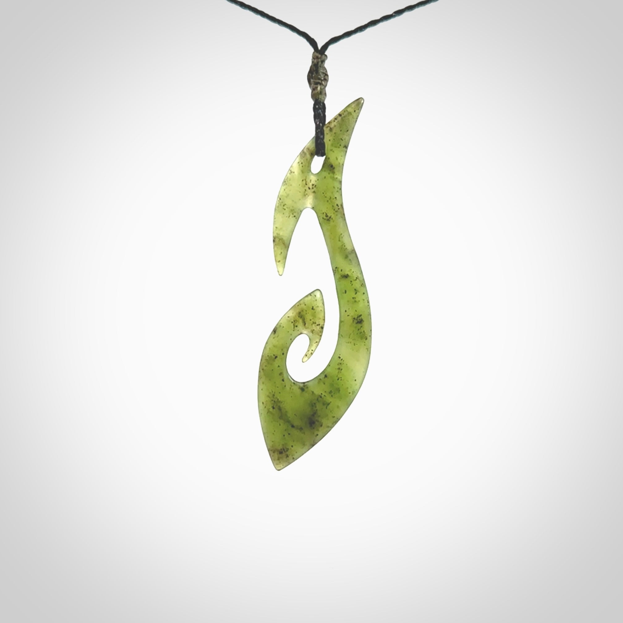 This photo shows a large contemporary matau pendant carved from New Zealand Jade. The artist, Shaun Gardiner, has carved this beautifully. We provide this piece with an adjustable black coloured cord. This is a fantastic work of art, we have one only.