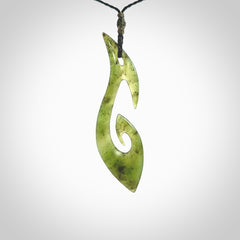 This photo shows a large contemporary matau pendant carved from New Zealand Jade. The artist, Shaun Gardiner, has carved this beautifully. We provide this piece with an adjustable black coloured cord. This is a fantastic work of art, we have one only.