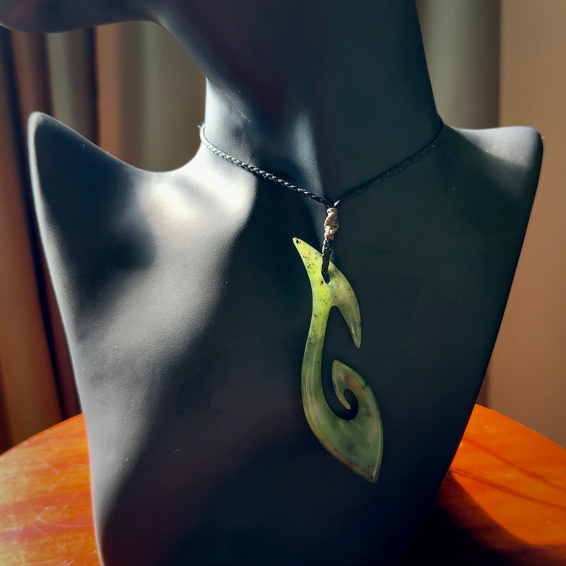 This photo shows a large contemporary matau pendant carved from New Zealand Jade. The artist, Shaun Gardiner, has carved this beautifully. We provide this piece with an adjustable black coloured cord. This is a fantastic work of art, we have one only.