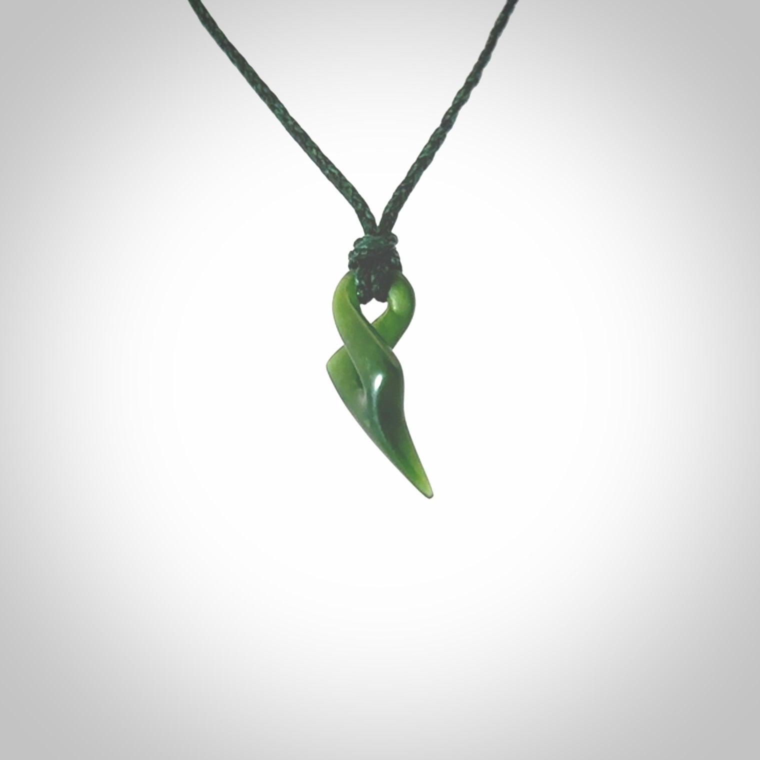 Hand carved small sized, New Zealand jade twist pendant. Carved in New Zealand by NZ Pacific. Hand made small Jade twist with adjustable manuka green cord by Shaun Gardiner.