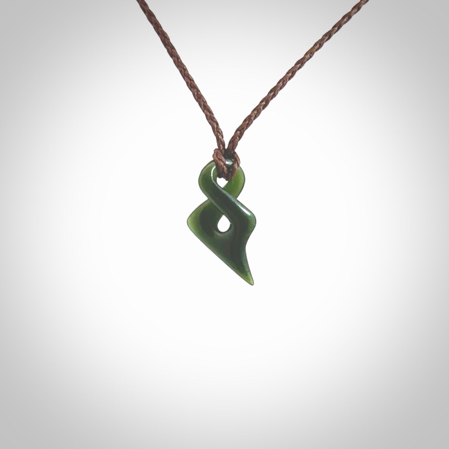 Hand carved small sized, New Zealand jade twist pendant. Carved in New Zealand by NZ Pacific. Hand made small Jade twist with adjustable brown cord by Shaun Gardiner.