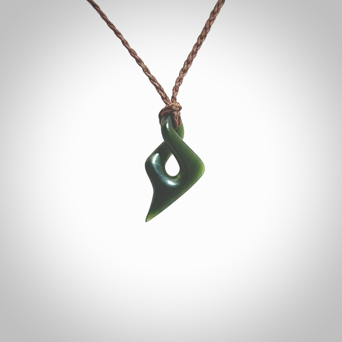 Hand carved small sized, New Zealand jade twist pendant. Carved in New Zealand by NZ Pacific. Hand made small Jade twist with adjustable brown cord by Shaun Gardiner.