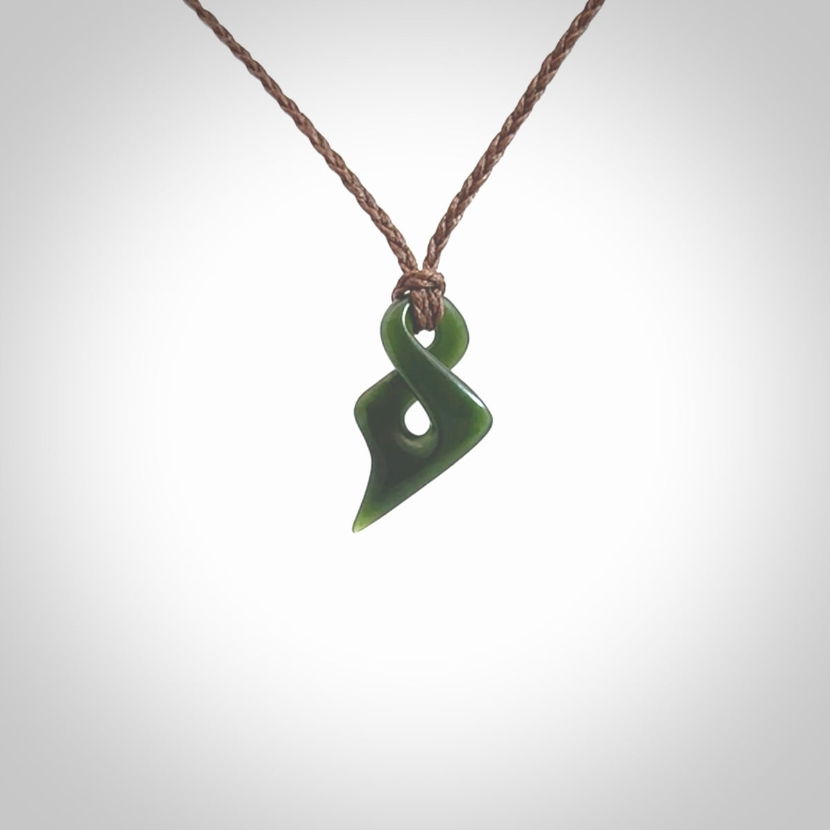 Hand carved small sized, New Zealand jade twist pendant. Carved in New Zealand by NZ Pacific. Hand made small Jade twist with adjustable brown cord by Shaun Gardiner.