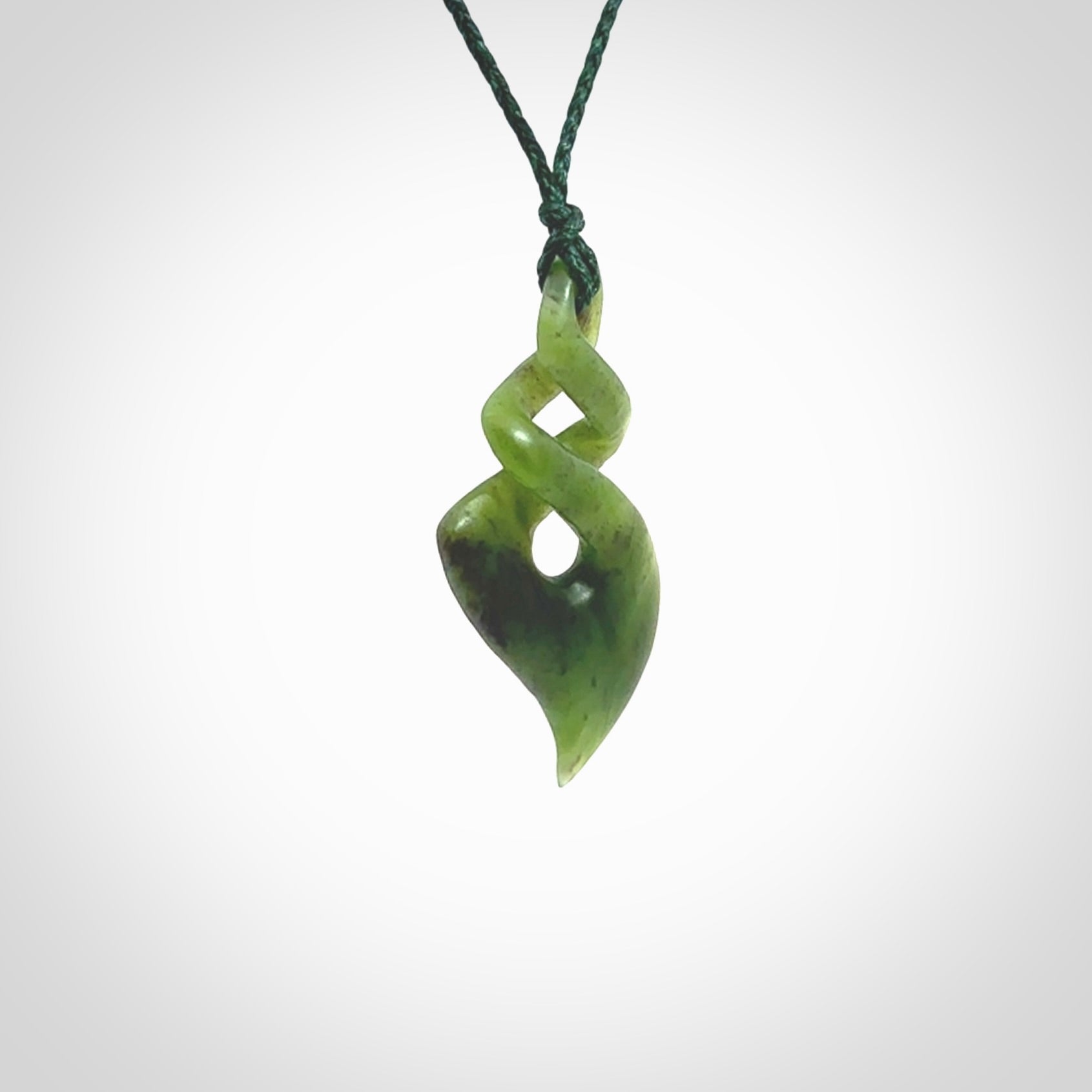 This is a striking, medium sized double twist pendant carved in New Zealand jade by Shaun Gardiner. Hand made Jade twist with adjustable green cord.