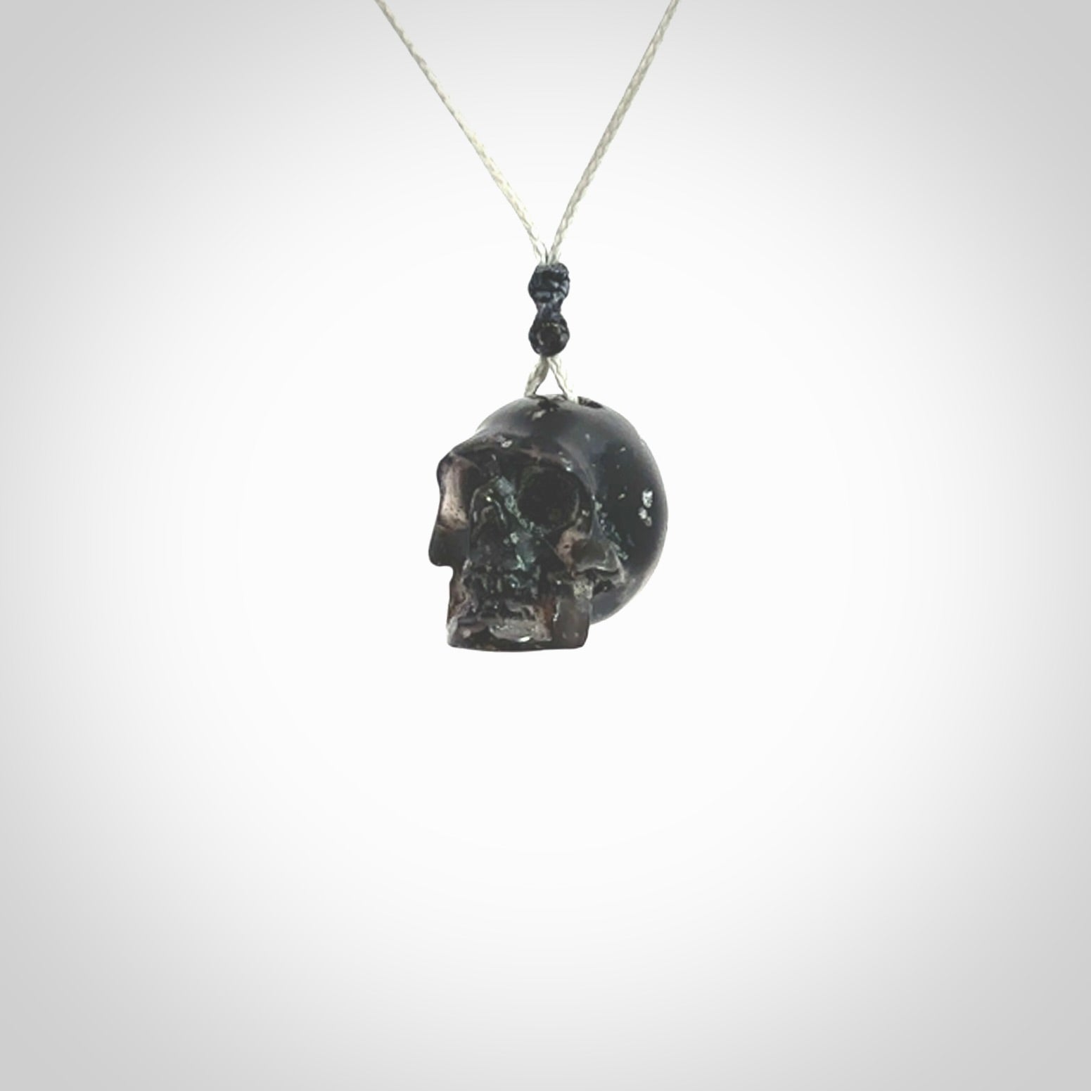 This picture shows a small sized Snowflake Obsidian stone skull pendant that we have hand carved. It is polished to a soft shine and is a very striking piece. Provided with an adjustable grey cord.