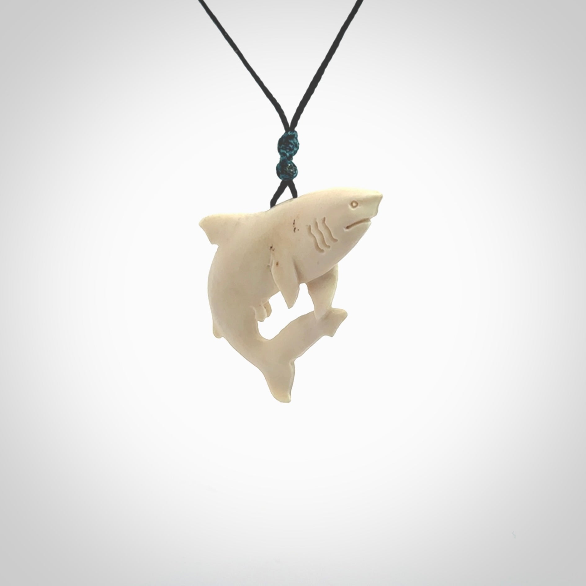 Hand carved shark pendant. Natural bone pendants from NZ Pacific. Provided with adjustable black cord and packaged in a woven kete pouch.