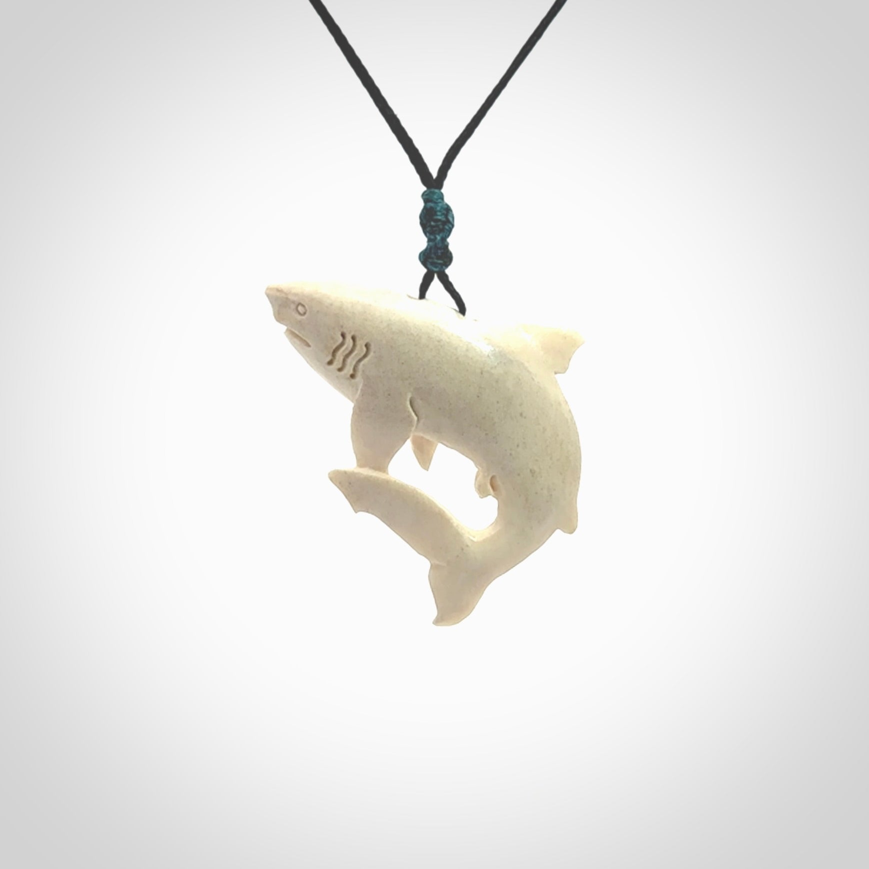 Hand carved shark pendant. Natural bone pendants from NZ Pacific. Provided with adjustable black cord and packaged in a woven kete pouch.