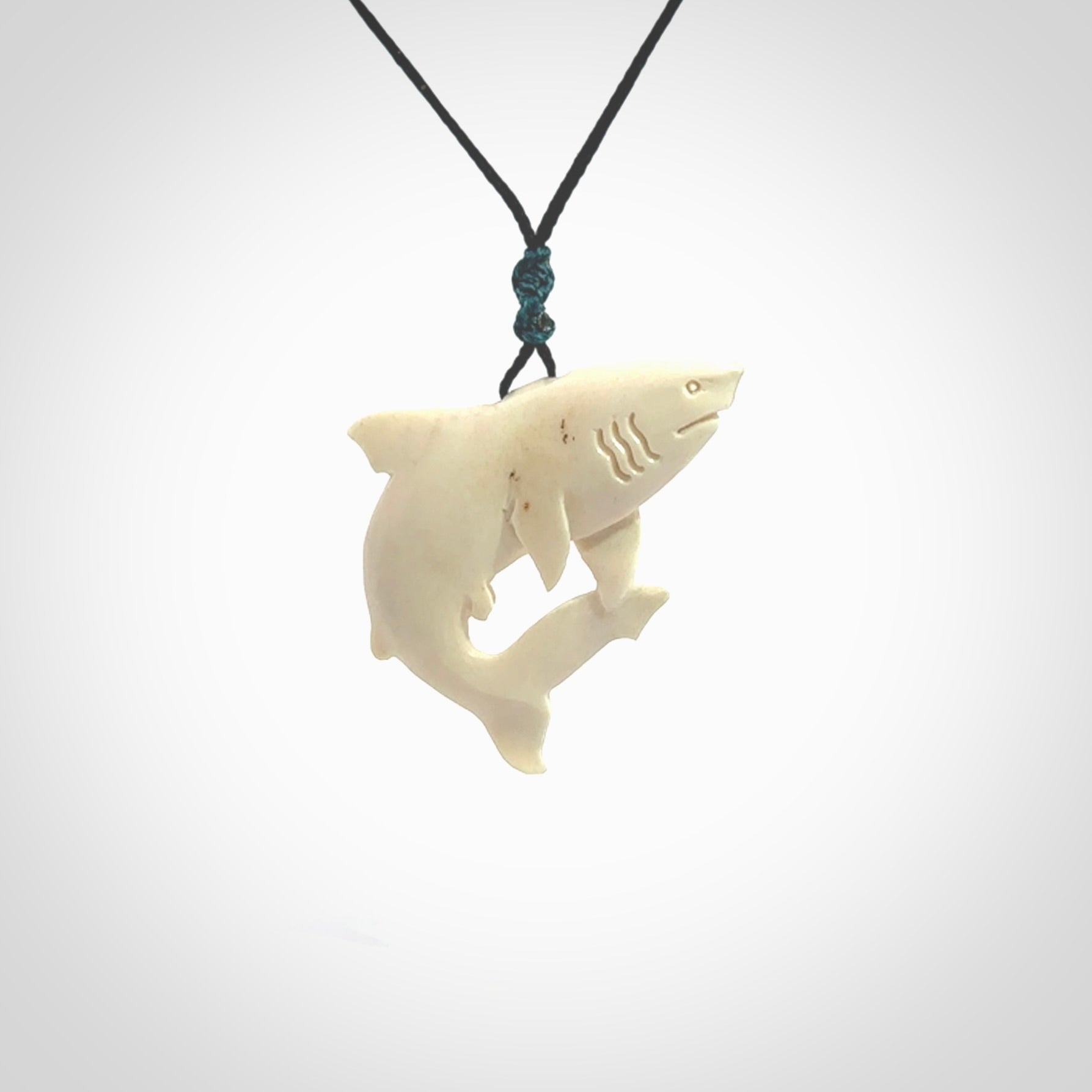 Hand carved shark pendant. Natural bone pendants from NZ Pacific. Provided with adjustable black cord and packaged in a woven kete pouch.