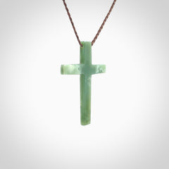 Hand carved jade cross. Made from New Zealand jade. Christian cross for sale online.This picture shows a green jade cross suspended on a fine, plaited cord. The cross is hand carved jade cross. Made from New Zealand jade. Christian cross for sale online.