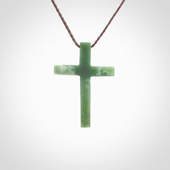 Hand carved jade cross. Made from New Zealand jade. Christian cross for sale online.This picture shows a green jade cross suspended on a fine, plaited cord. The cross is hand carved jade cross. Made from New Zealand jade. Christian cross for sale online.