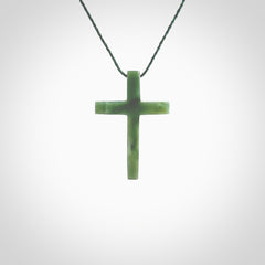 Hand carved jade cross. Made from New Zealand jade. Christian cross for sale online.This picture shows a green jade cross suspended on a fine, plaited cord. The cross is hand carved jade cross. Made from New Zealand jade. Christian cross for sale online.