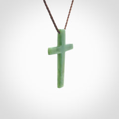 Hand carved jade cross. Made from New Zealand jade. Christian cross for sale online.This picture shows a green jade cross suspended on a fine, plaited cord. The cross is hand carved jade cross. Made from New Zealand jade. Christian cross for sale online.