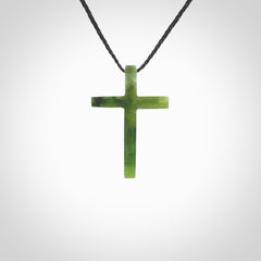 Hand carved jade cross. Made from New Zealand jade. Christian cross for sale online.This picture shows a green jade cross suspended on a fine, plaited cord. The cross is hand carved jade cross. Made from New Zealand jade. Christian cross for sale online.