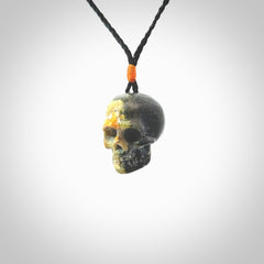 This picture shows a medium sized Bumblebee Jasper stone skull pendant that we have hand carved. It is polished to a soft shine and is a very striking piece. The cord is black colour and has a small orange popper binding just above the pendant.