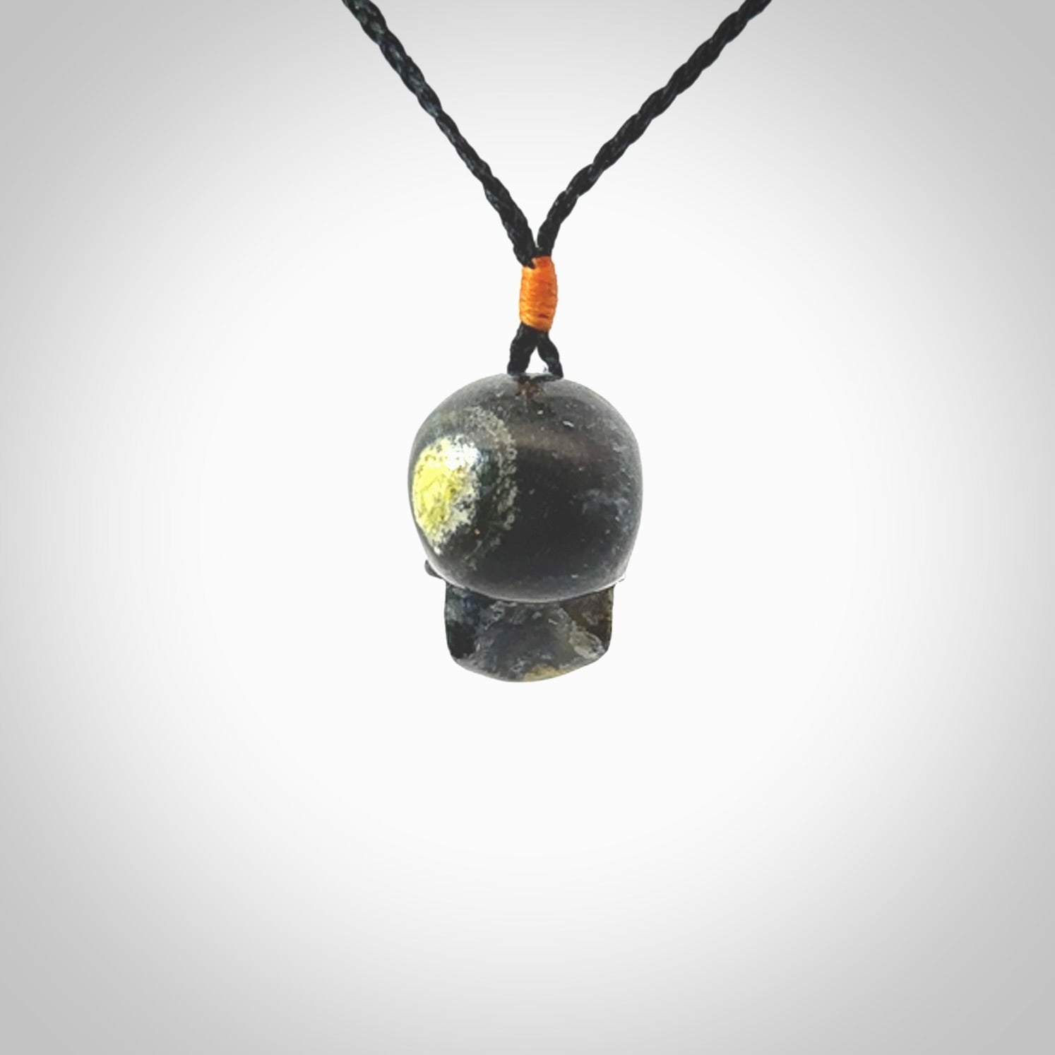 This picture shows a medium sized Bumblebee Jasper stone skull pendant that we have hand carved. It is polished to a soft shine and is a very striking piece. The cord is black colour and has a small orange popper binding just above the pendant.