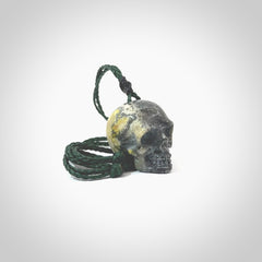 This picture shows a medium sized Bumblebee Jasper stone skull pendant that we have hand carved. It is polished to a soft shine and is a very striking piece. The cord is green colour and has a small black floret binding just above the pendant.