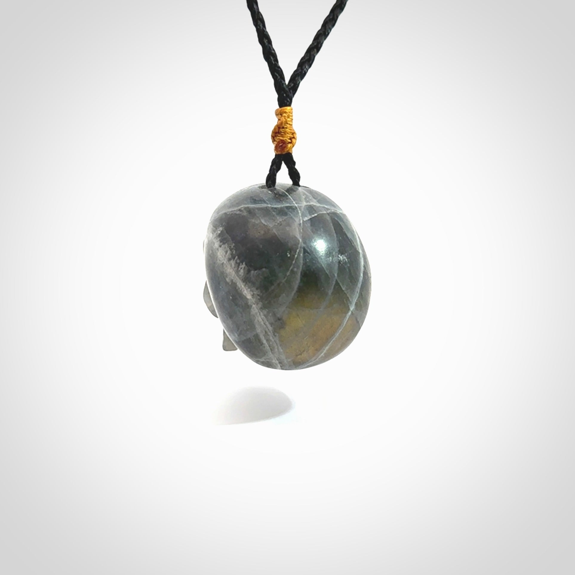 This picture shows a large sized Labradorite skull pendant that we have hand carved. It is polished to a soft shine and is a very striking piece. The cord is black and has a small gold floret binding just above the pendant.