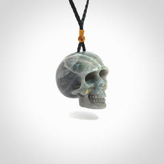 This picture shows a large sized Labradorite skull pendant that we have hand carved. It is polished to a soft shine and is a very striking piece. The cord is black and has a small gold floret binding just above the pendant.