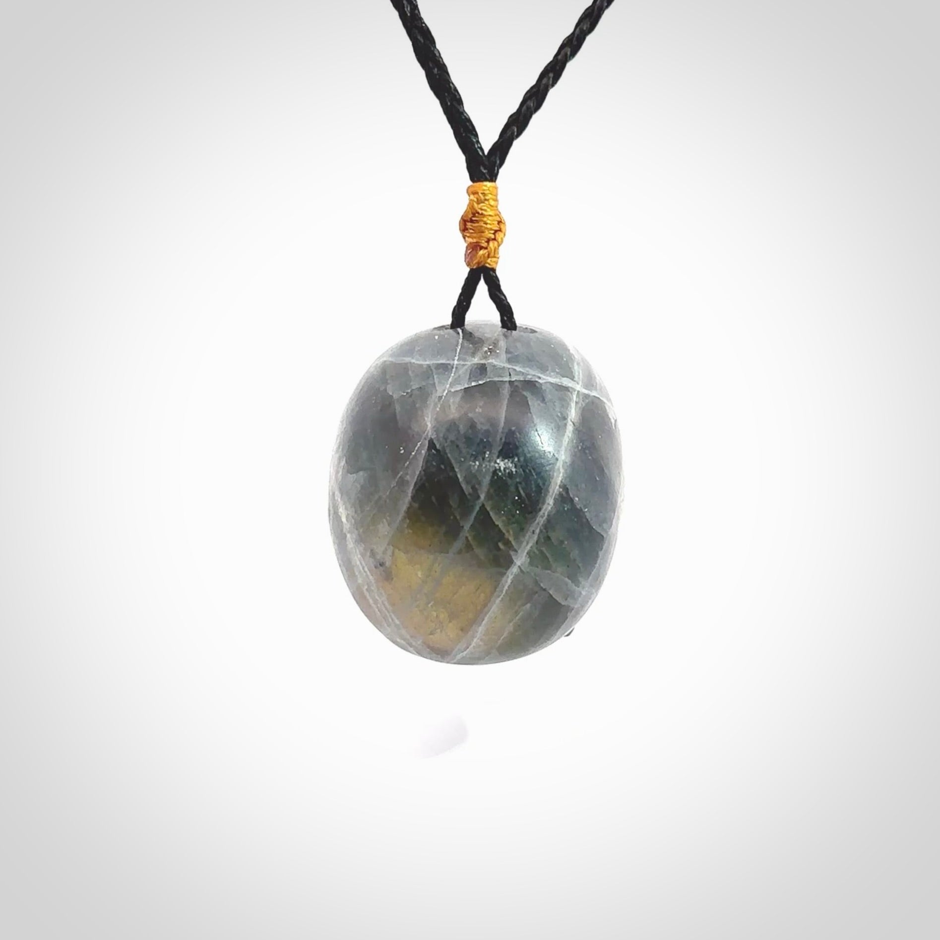 This picture shows a large sized Labradorite skull pendant that we have hand carved. It is polished to a soft shine and is a very striking piece. The cord is black and has a small gold floret binding just above the pendant.