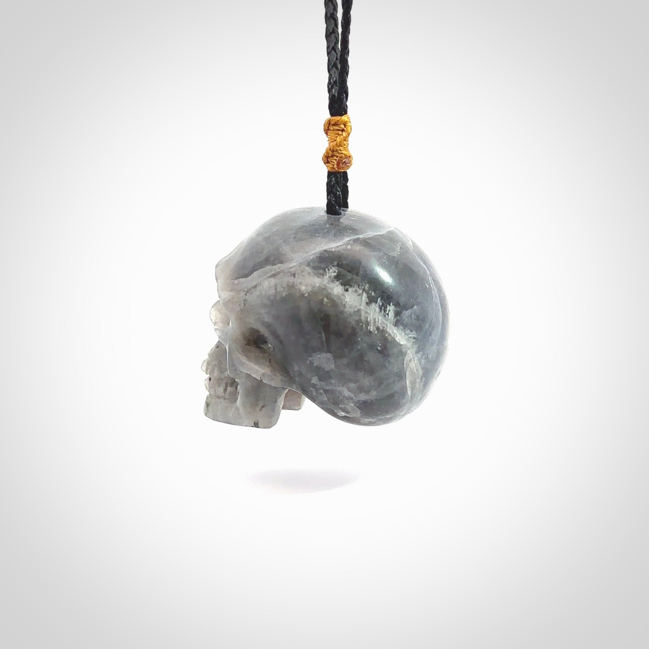 This picture shows a large sized Labradorite skull pendant that we have hand carved. It is polished to a soft shine and is a very striking piece. The cord is black and has a small gold floret binding just above the pendant.