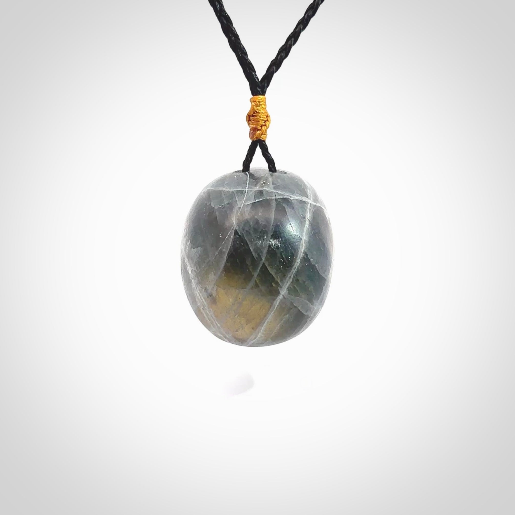 This picture shows a large sized Labradorite skull pendant that we have hand carved. It is polished to a soft shine and is a very striking piece. The cord is black and has a small gold floret binding just above the pendant.