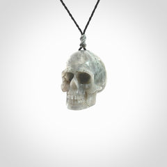 This picture shows a large sized Grey Moonstone skull pendant that we have hand carved. It is polished to a soft shine and is a very striking piece. The cord is black and has a small grey floret binding just above the pendant.