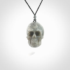 This picture shows a large sized Grey Moonstone skull pendant that we have hand carved. It is polished to a soft shine and is a very striking piece. The cord is black and has a small grey floret binding just above the pendant.