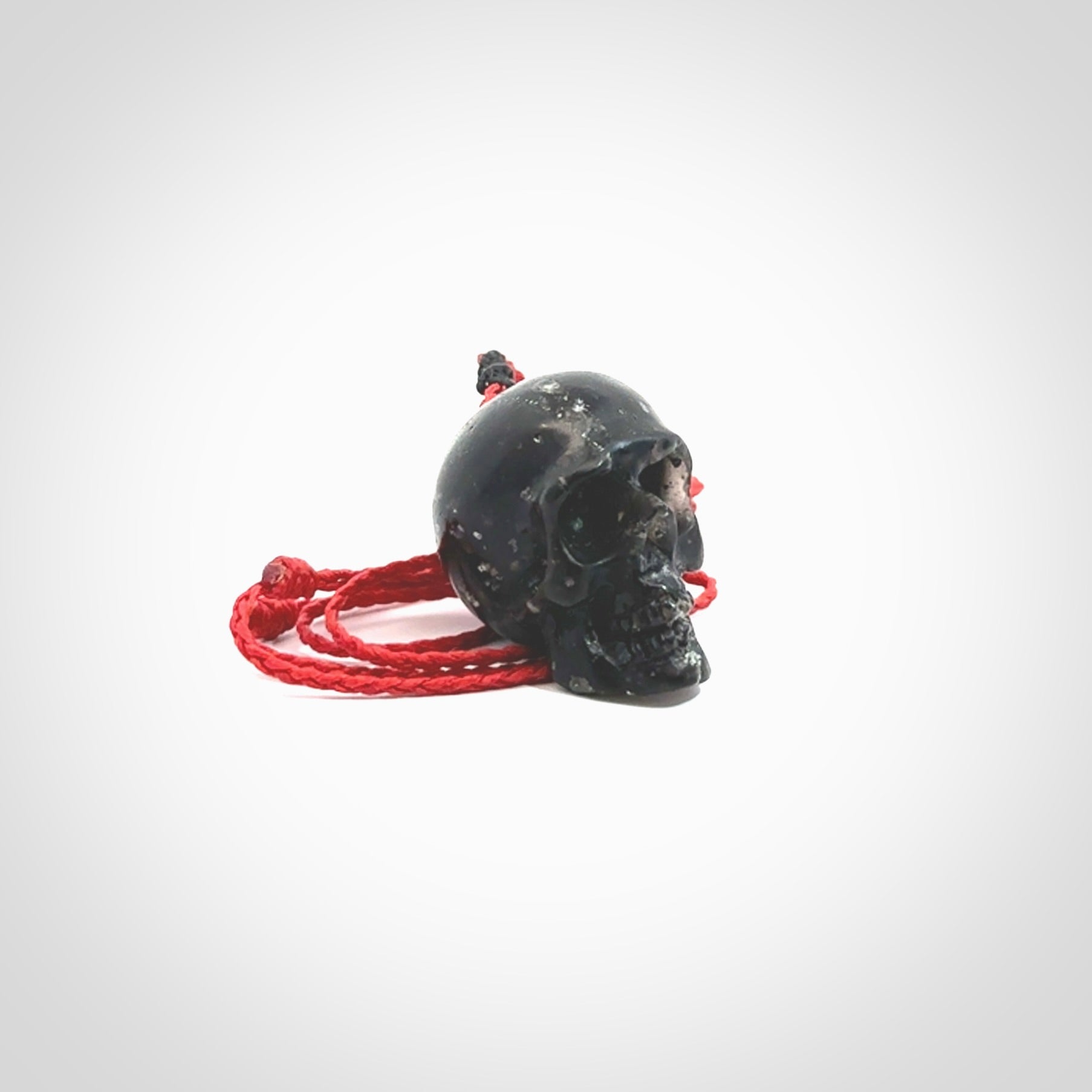 This picture shows a large sized Snowflake Obsidian stone skull pendant that we have hand carved. It is polished to a soft shine and is a very striking piece. Provided with an adjustable red cord.