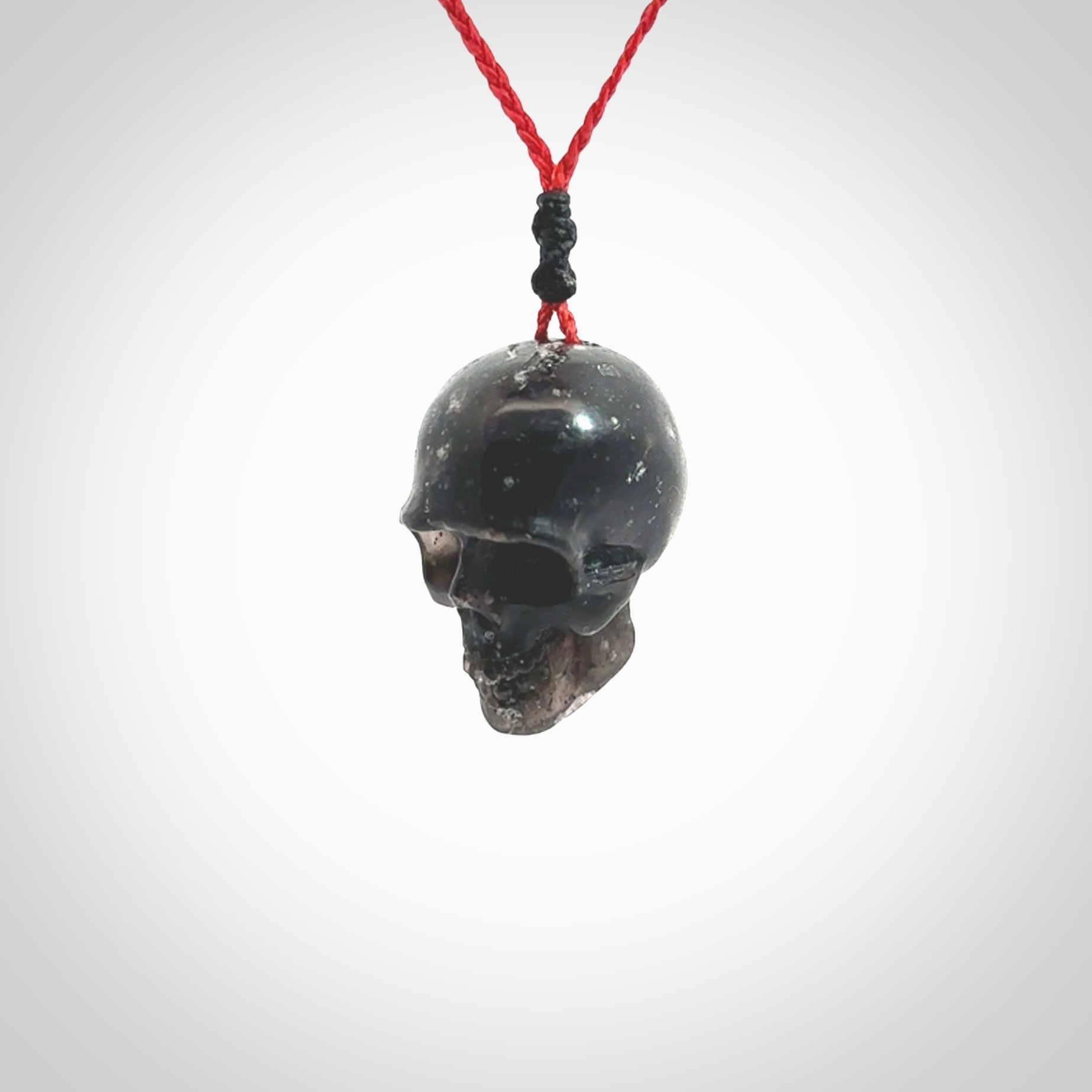 This picture shows a large sized Snowflake Obsidian stone skull pendant that we have hand carved. It is polished to a soft shine and is a very striking piece. Provided with an adjustable red cord.