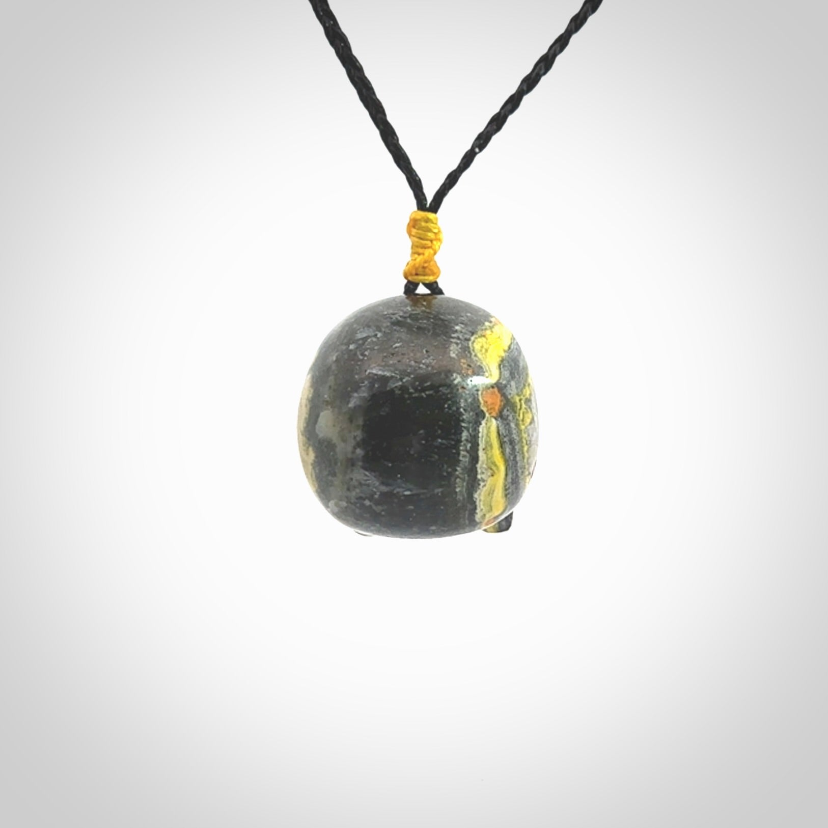 This picture shows a large sized Bumblebee Jasper stone skull pendant that we have hand carved. It is polished to a soft shine and is a very striking piece. The cord is a black colour and has a small yellow floret binding just above the pendant.